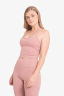 Mujer joven con ropa deportiva rosa, top sin mangas y leggings, fondo blanco