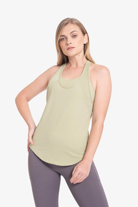 Mujer rubia con camiseta deportiva verde claro y leggings morados en fondo blanco
