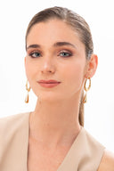 Retrato de mujer con maquillaje natural y pendientes dorados colgantes, fondo blanco