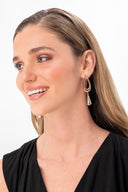 Mujer con maquillaje natural y aretes dorados modernos en estudio con fondo blanco