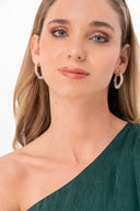 Mujer con aretes grandes de aro y vestido verde asimétrico, fondo blanco