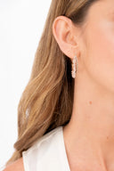 Pendiente de aro con detalles brillantes y flores transparentes en oreja de mujer con cabello rubio