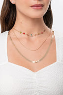 Collares dorados y collar con piedras de colores en cuello de mujer con blusa blanca