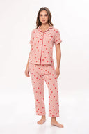 Mujer con pijama rosa con estampado de corazones rojos, camisa de botones y pantalón largo