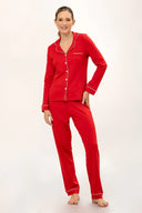 Mujer con pijama rojo de manga larga y pantalón largo con detalles blancos, fondo blanco