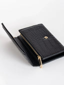 Billetera negra de cuero con textura de cocodrilo y cremallera dorada, sobre fondo blanco