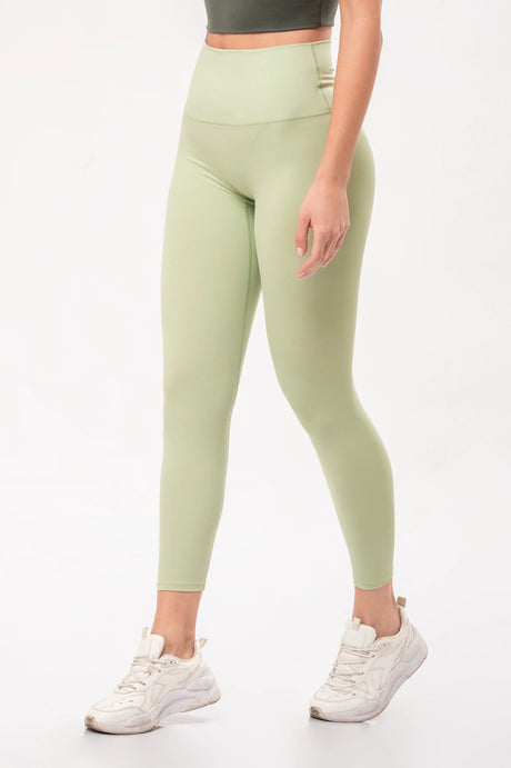 Leggings deportivos altos en color verde claro combinados con zapatillas blancas para ejercicio